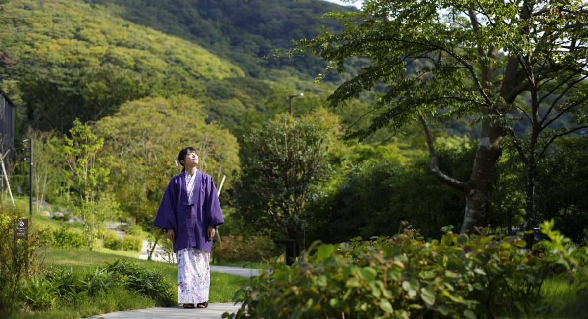 自然豊かな里山の中を着物姿で散策する女性
