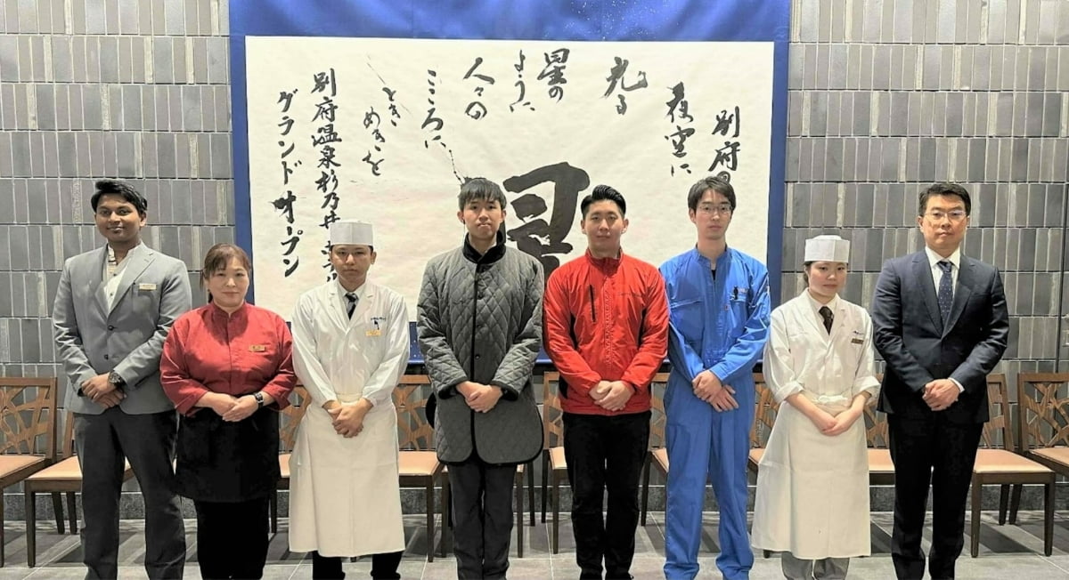 多様な職種のスタッフが一堂に並ぶ集合写真。互いを尊重し成長を支え合う、働きがいのある職場づくりを表現